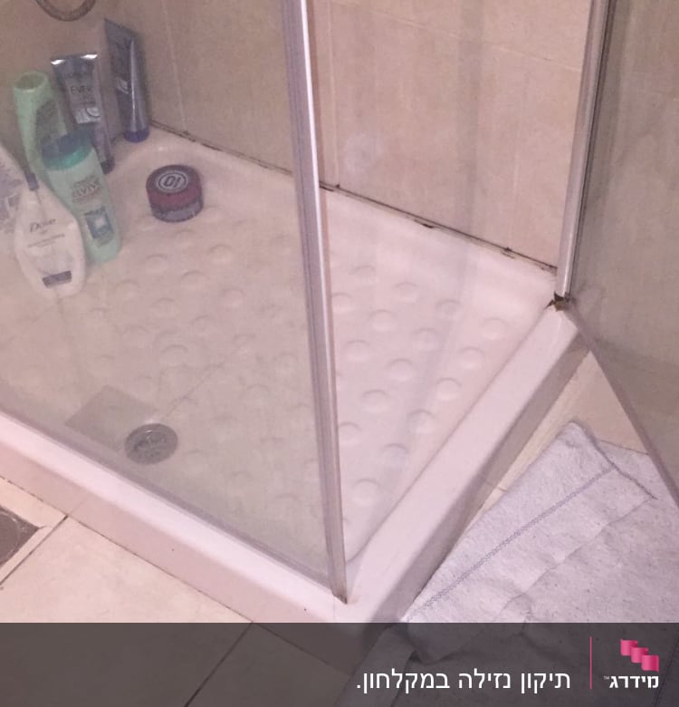 מקלחון עם מגבת על הרצפה ליד הניקוז